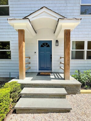 A house with a blue door, a porch with steps, and a small garden.