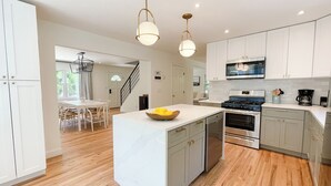A modern kitchen with white cabinetry, a central island, stainless steel appliances, and a wooden floor.