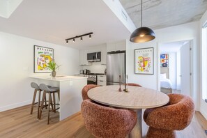 Une cuisine moderne dotée d’un îlot central, de tabourets de bar et d’une table à manger avec un design de chaises original.