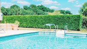A rectangular swimming pool with clear blue water, surrounded by a hedge and a white deck with lounge chairs. - Peace, nature and old stones (Berthenay)
