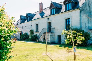 Ein Gebäude aus Stein mit Balkon, Treppe und einem kleinen Garten.