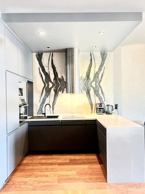 Una cocina moderna con una isla central, una campana extractora de acero inoxidable y un salpicadero con diseños abstractos en blanco y negro.