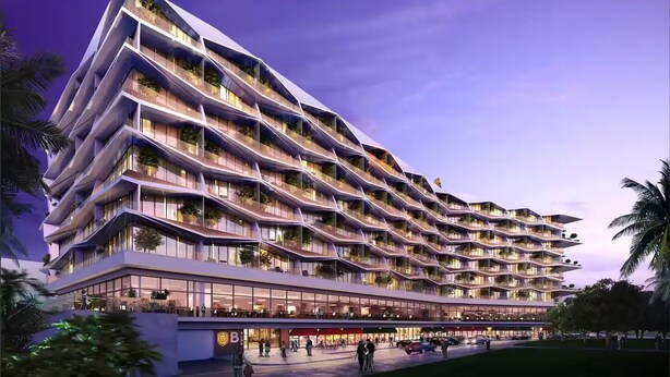 Un hotel moderno con varios balcones, una entrada espaciosa y una zona ajardinada.