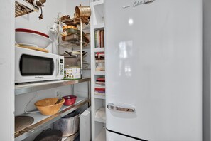 A kitchen with a white refrigerator, a microwave, shelves with cookware, and a wooden bowl. - Charming Virginia Horse Country Retreat (Marshall)
