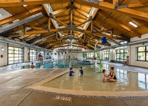 Ein Hallenbad mit hoher Holzdecke und großen Fenstern.