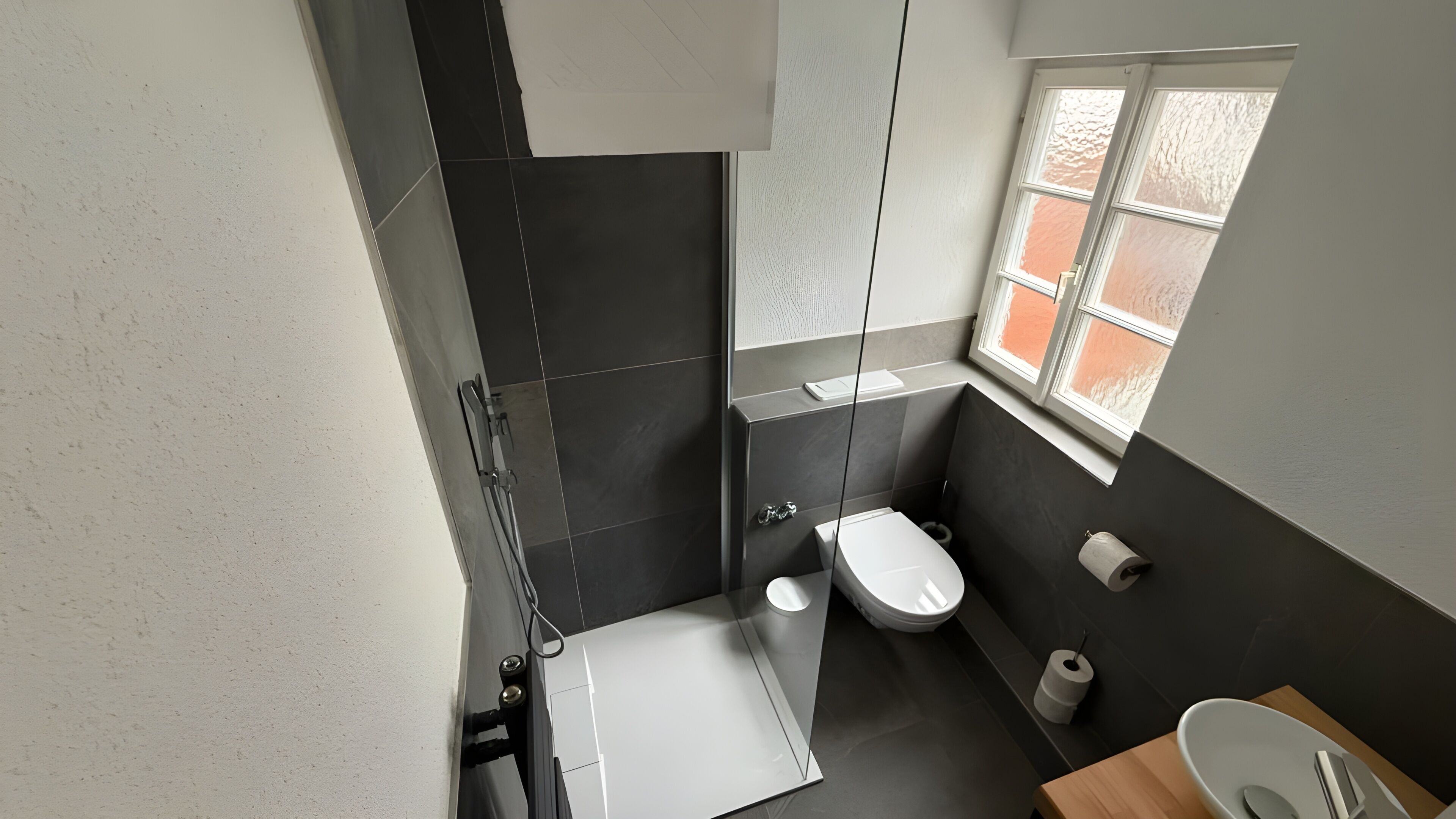 A modern bathroom with a shower, toilet, and sink.