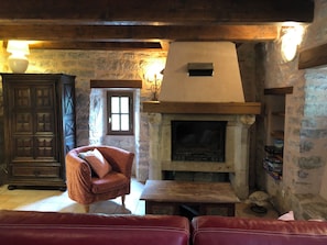 Ein rustikales Interieur mit Kamin aus Stein, Holzmöbeln und einer gemütlichen Sitzecke.