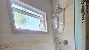 Ein Badezimmer mit Dusche, Fenster und Handtuchhalter.
