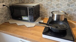 Eine Küche mit Mikrowelle, einem Topf auf dem Herd und einer Bratpfanne.