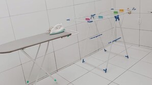 A room with a metal ironing board, an iron, and a drying rack with clothes. - Comfort and Style | 7 Min Walk from Parque do Povo. (Campina Grande)
