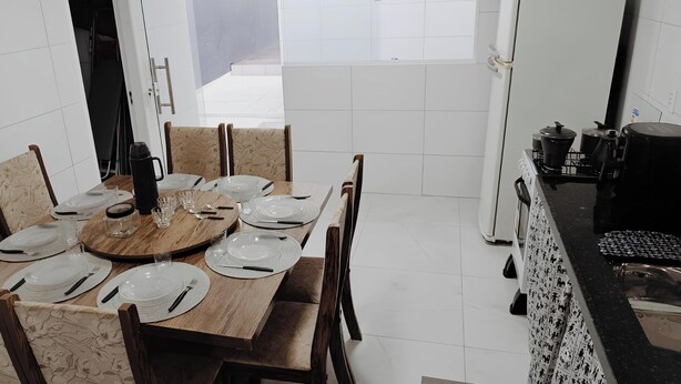A dining area with a round table set for six, surrounded by chairs. - Comfort and Style | 7 Min Walk from Parque do Povo. (Campina Grande)