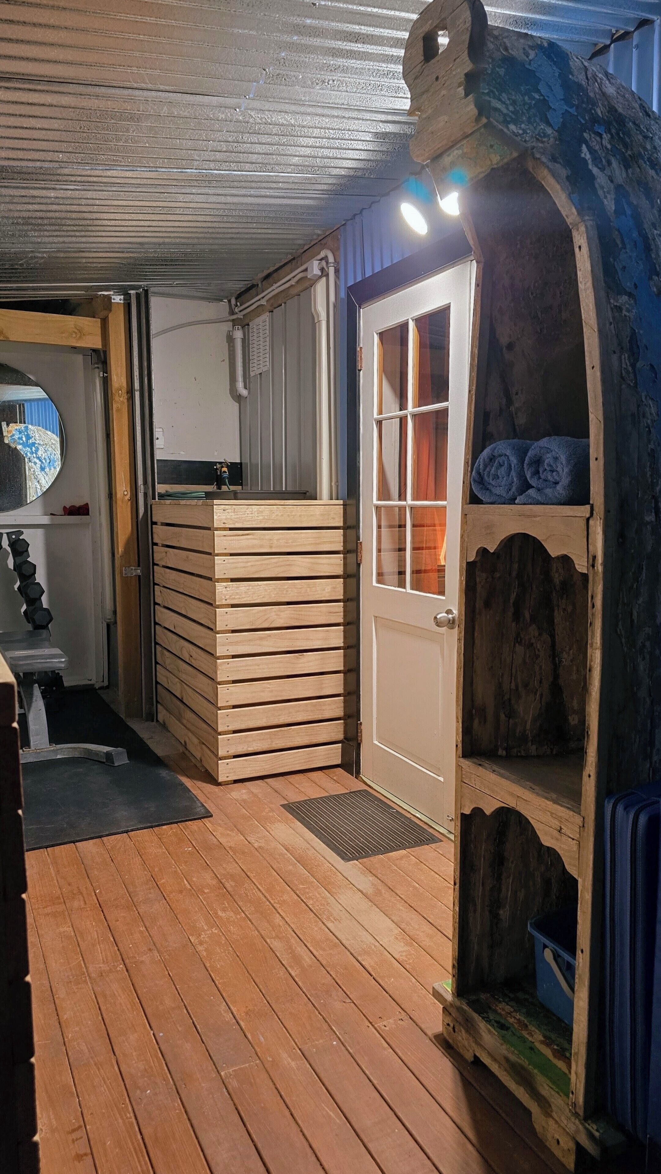 A wooden deck with a door and a small wooden structure with a window.