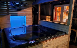 Eine Holzwanne im Spa-Bereich mit Bedienfeld, Schmetterlingsdeko und einem Fenster mit Vorhängen.