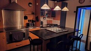 Eine moderne Küche mit Dunstabzugshaube aus Edelstahl, einer Kaffeemaschine, einer Mikrowelle und einem Schachbrett auf der Arbeitsplatte.
