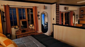 Ein Schlafzimmer mit Bett, Kommode, Spiegel und einem Fenster mit Vorhängen.