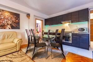 Una cocina moderna con armarios oscuros, una mesa de comedor de vidrio y un sofá en la sala.
