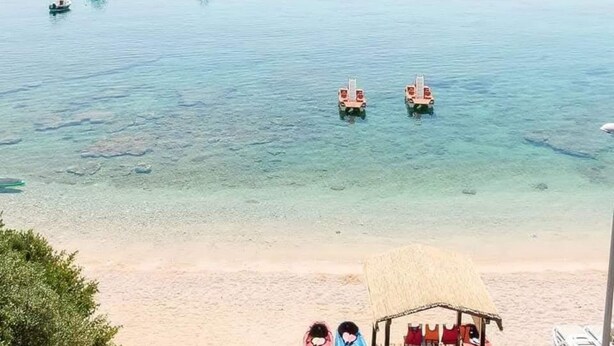 A beach with clear water, a thatched hut, and a small boat. - Apartman Helena Korčula (Blato)
