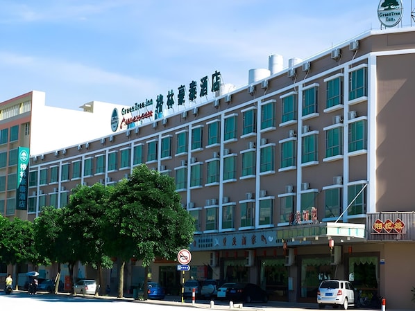 Ett hotell med flera våningar, med en tydlig skylt som visar namnet ”GreenTree Inn”.