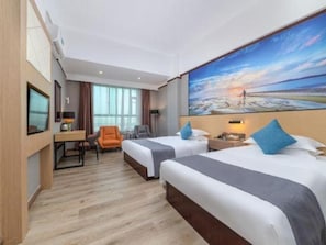 Ein Hotelzimmer mit zwei Betten, einem Schreibtisch, einem Stuhl und einem großen Gemälde mit Strandmotiv.