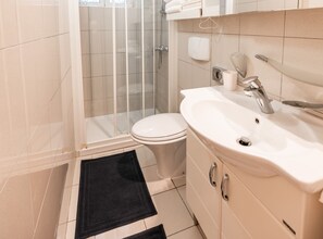 A bathroom with a toilet, sink, and shower.