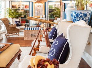 A cozy living room with a vintage telescope, wicker furniture, and a bookshelf filled with books.