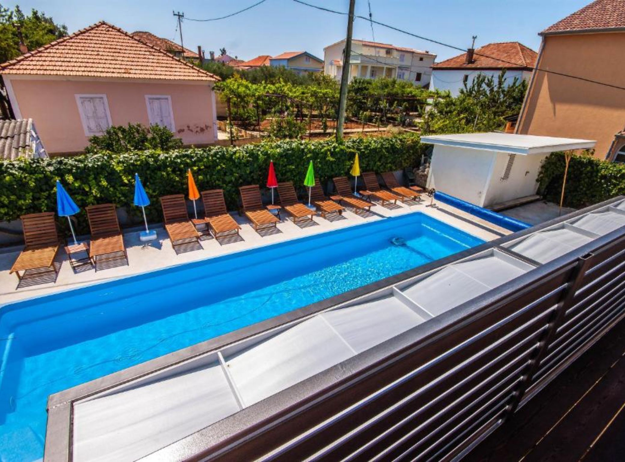A swimming pool with lounge chairs and umbrellas, surrounded by buildings.