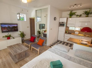 Ein modernes Apartment mit Wohnbereich, Küche und einem an der Wand befestigten Fernseher.