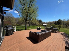 A wooden deck with outdoor furniture, a grill, and a dining table. - Litchfield Hills Modern Design Escape w/ a Pool (Sharon)