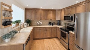 Uma cozinha moderna com armários de madeira, eletrodomésticos de aço inoxidável e forno embutido.