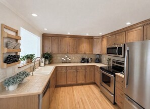 Eine moderne Küche mit Holzschränken, Edelstahlgeräten und einem eingebauten Backofen.