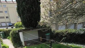 A residential area with a pathway, a tall tree, and a building in the background. - Family room with private garden area + barbecue (Niort)
