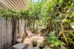 Un jardín con cerco de madera, una banca y diversas plantas.