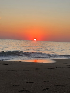 Un atardecer sobre el océano con olas acercándose a la orilla.