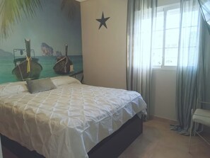Ein Schlafzimmer mit einem Bett, einer Wanddekoration mit Sternen und einem Fenster mit Vorhängen.