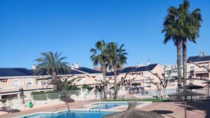 A swimming pool with a thatched umbrella, palm trees, and a view of residential buildings. - ☀️🏖️ A DREAM VACATION AT PLAYA EL CARABASSÍ (ALICANTE)☀️🏖️ (Gran Alacant)