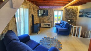 Ein gemütliches Wohnzimmer mit Steinwand, Kamin, einem blauen Sofa und einem Fernseher.