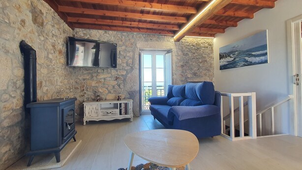 Ein gemütliches Zimmer mit einer Steinsturz, einem blauen Sofa, einem kleinen Tisch und einer Holzbalkendecke.