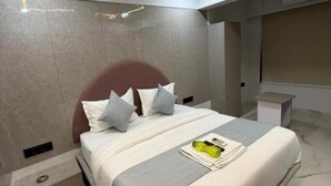 Una habitación de hotel moderna con una cama grande, ventilador de techo, iluminación empotrada y suelo de mármol.