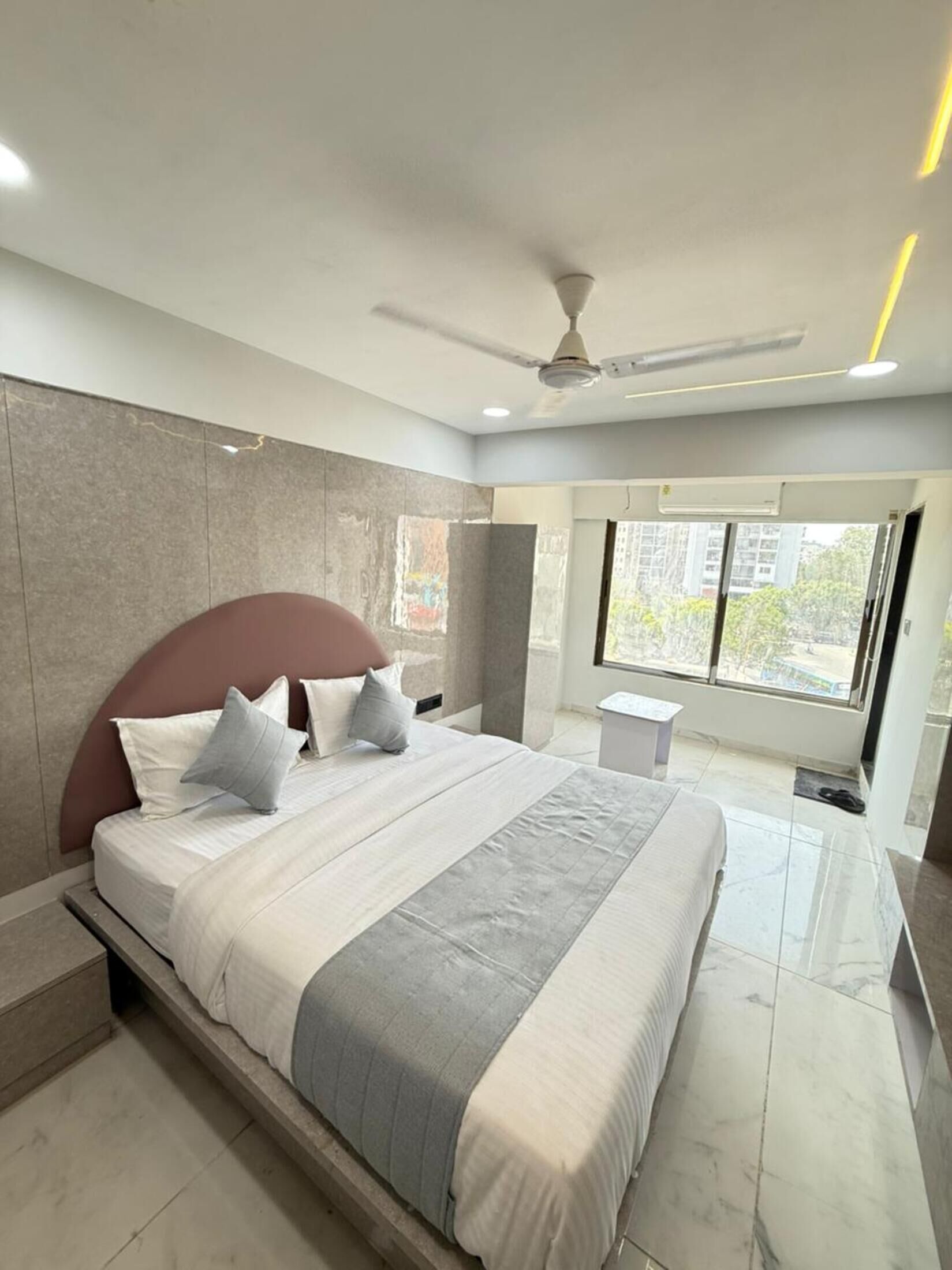 Ein modernes Schlafzimmer mit einem großen Bett, einem Deckenventilator und einem Fenster mit Blick auf die Stadt.