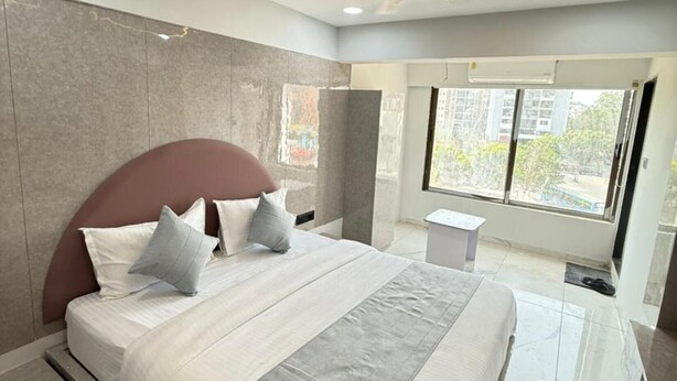 Un dormitorio moderno con una cama grande, ventilador de techo y ventana con vista a la ciudad.
