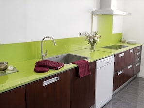 Eine moderne Küche mit grüner Arbeitsplatte, Spüle aus Edelstahl und Holzschränken.