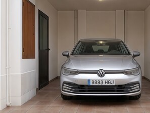 Ein silberfarbener VW Wagen steht in einem modernen, gut beleuchteten Innenraum mit weißen Wänden und einer Holztür.