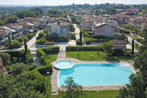A residential area with a swimming pool surrounded by well-maintained lawns and trees. - Francy House: Pool, Relaxation, Lake Garda, A/C, WiFi (Castelnuovo del Garda)