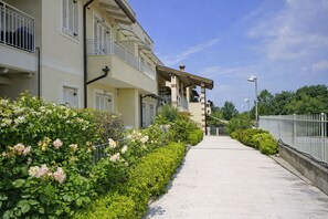 A residential building with balconies, a paved walkway, and a metal fence. - Francy House: Pool, Relaxation, Lake Garda, A/C, WiFi (Castelnuovo del Garda)