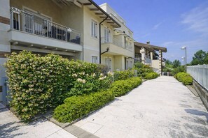 A residential building with multiple balconies, a paved walkway, and well-maintained greenery. - Francy House: Pool, Relaxation, Lake Garda, A/C, WiFi (Castelnuovo del Garda)