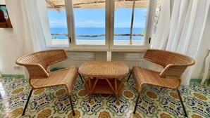 Una habitación con vista al mar, una mesa de mimbre y dos sillas.