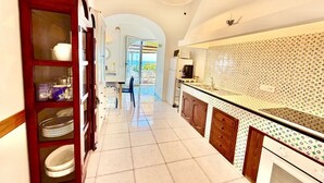 Una cocina con salpicadero de azulejos, armarios de madera y vista a un espacio exterior mediante un arco.