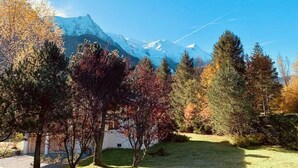 A mountainous landscape with a clear sky, trees in autumn colors, and a building in the foreground. - Our family chalet in the heart of the Alps (Chamonix-Mont-Blanc)