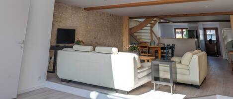 A spacious living area with a high ceiling, skylights, a staircase, and a modern kitchen.