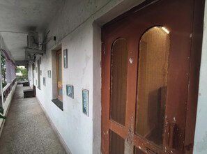 A corridor with a wooden door, white walls, and framed pictures.